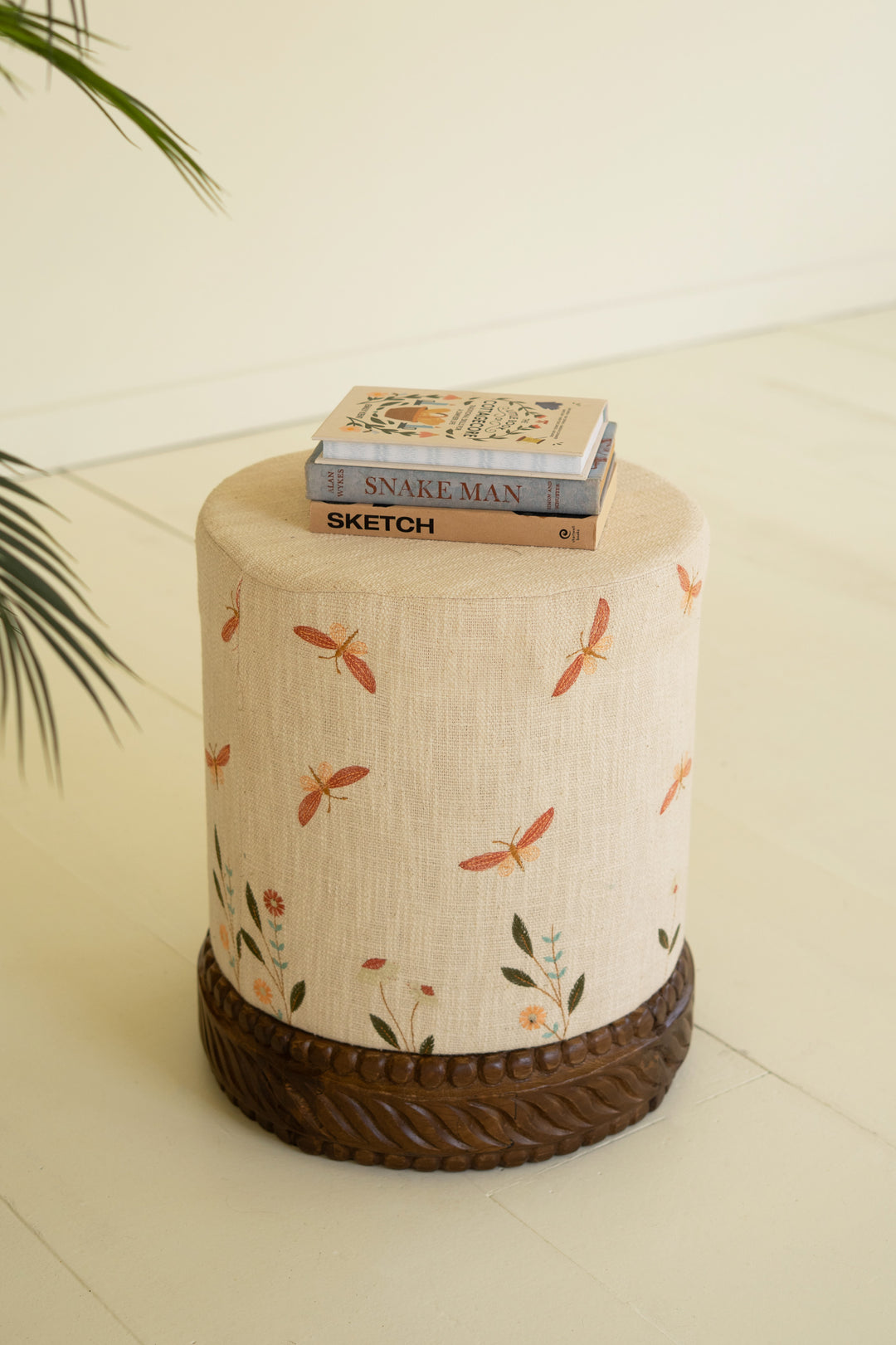 Cream Upholstered Ottoman with Embroidered Detail and Carved Wood Base