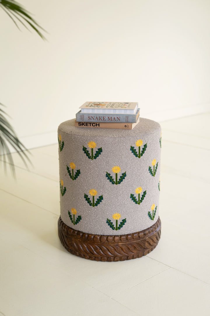 Grey Upholstered Ottoman with Embroidered Detail and Carved Wood Base