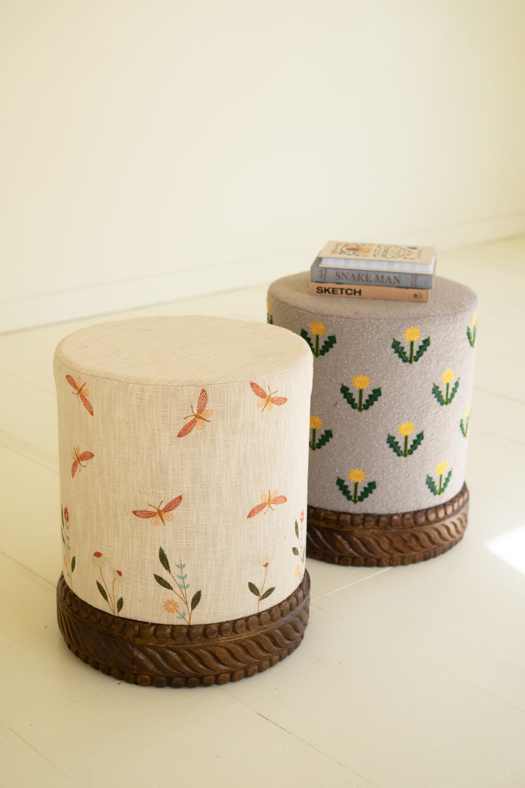 Grey Upholstered Ottoman with Embroidered Detail and Carved Wood Base