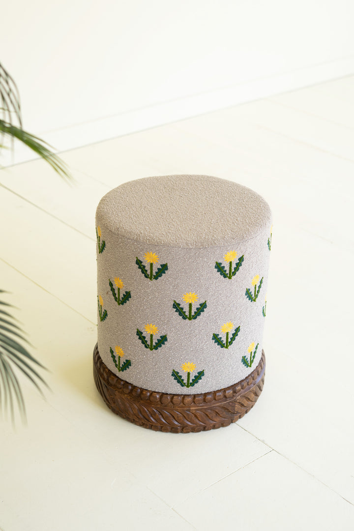 Grey Upholstered Ottoman with Embroidered Detail and Carved Wood Base